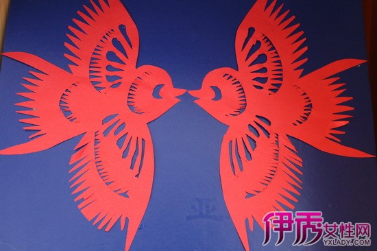 一、点染剪纸 以颜色在刻纸上进行点色为点染剪纸。这种剪纸也属于刻纸,在设计上阳线不多,偏重干小面积的阴刻,以留出大面积的阳面进行点染。类似于木版年画的效果。 点染剪纸所用颜色,一般系民间染布用的品红、品绿等,统称品色。染到用白生宣纸刻成的剪纸上。品色一融到生宣纸,便立即上下左右渗透扩散开来,一次可染三五张。渗透不足的部位,可翻过来在背面补笔。调制时掺入白酒或酒精,渗透性很强,用在宣纸等吸水性较强的纸质上。由于酒精和白酒中不含胶,酒精挥发后纸面依然平整,不起皱,能产生较好的晕染效果。 点染时,一支毛笔蘸